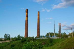 tubos de fábrica no fundo da grama verde e céu azul com nuvens. foto