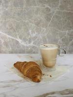 xícara de café de vidro com croissant no fundo foto