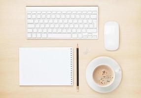 mesa de escritório com bloco de notas, computador e xícara de café
