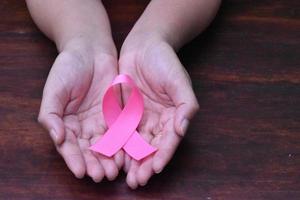 a fita rosa na mão, símbolo da campanha mundial contra o câncer de mama feminino. foto