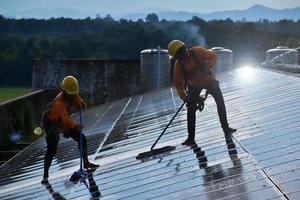 técnicos fotovoltaicos estavam limpando e lavando a superfície dos painéis solares que tinham poeira e cocô de pássaros foto