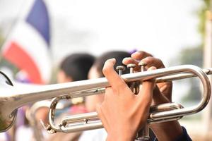 estudante asiático soprando um trompete com a banda marcial da escola, fundo desfocado foto