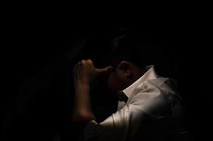 homem deprimido miserável asiático sentado sozinho no fundo escuro. depressão e conceito de saúde mental. foto