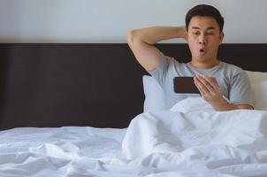 homem asiático assistindo notícias surpresa on-line no telefone inteligente foto