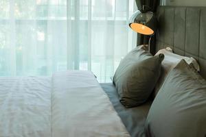 lâmpada de mesa de metal e travesseiro cinza na cama foto