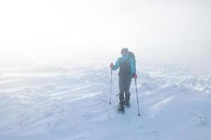 uma mulher no inverno trekking durante o nevoeiro foto