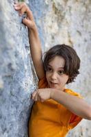 um pequeno alpinista está treinando para escalar uma pedra foto