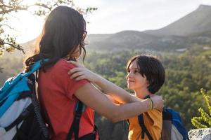 viajando com crianças, mulher e uma criança ao amanhecer no topo de uma montanha foto