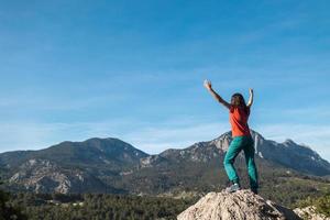 uma jovem subiu ao topo da montanha e colocou as mãos para cima foto