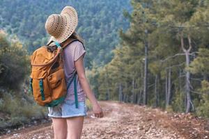 uma mulher com uma mochila e um chapéu de palha em um caminho de montanha foto