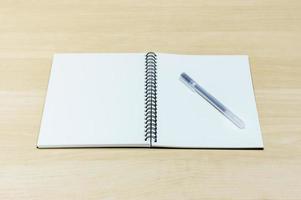 caneta e caderno na mesa de madeira foto