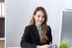 retrato de jovem empresária asiática está feliz em trabalhar no escritório moderno usando um computador portátil. conceito de telemarketing de comércio eletrônico freelance de empregado de negócios. foto
