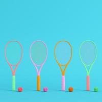 raquetes de tênis coloridas com bolas em fundo azul brilhante em tons pastel. conceito de minimalismo foto