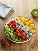 tigela de salada de frutas frescas saudável, fruta do dragão, kiwi, manga, morango, em cima da mesa. imagem de foco selecionada.