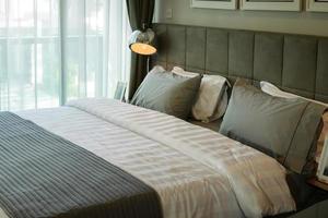 lâmpada de mesa de metal e travesseiro cinza na cama foto