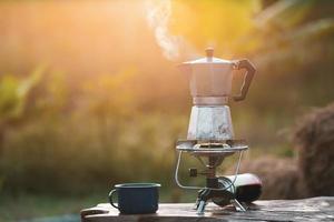 cafeteira antiga no fogão a gás para acampar quando o sol nasce de manhã. foto