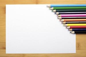 papel em branco e lápis coloridos em cima da mesa de madeira. foto