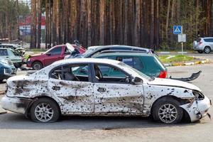 um carro destruído por estilhaços de um foguete que explodiu nas proximidades. cemitério de automóveis irpensky. consequências da invasão do exército russo na ucrânia. ucrânia, irpen - 12 de maio de 2022. foto