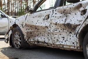 um carro destruído por estilhaços de um foguete que explodiu nas proximidades. cemitério de automóveis irpensky. consequências da invasão do exército russo na ucrânia. ucrânia, irpen - 12 de maio de 2022. foto