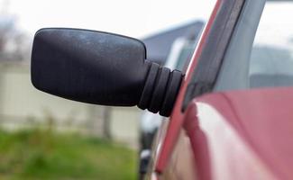 espelho retrovisor de plástico lado esquerdo direito em um carro vermelho. espelho de vista lateral exterior no lado do passageiro em um carro antigo. foto