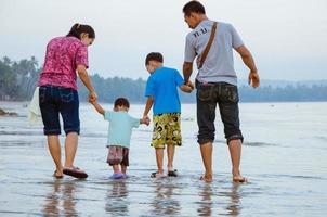família asiática passeando na praia. foto