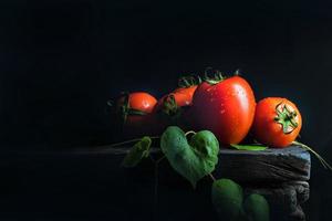 tomate vegetal e folha verde no velho piso de madeira escuro preto antigo foto