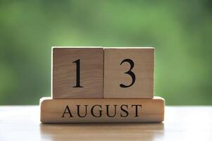13 de agosto texto de data de calendário em blocos de madeira com parque de fundo desfocado. copie o conceito de espaço e calendário foto