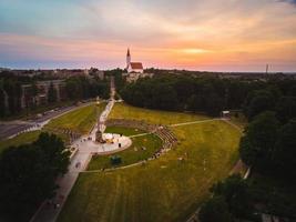 siauliai, lituânia, 2021 - vista panorâmica aérea do panorama da cidade de siauliai no verão com um belo pôr do sol e as pessoas desfrutam de concertos ao vivo da famosa estátua de menino dourado foto