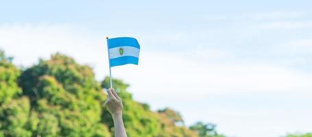 mão segurando a bandeira argentina no fundo da natureza. 9 de julho do dia da independência, 25 de maio do dia da revolução e conceitos de celebração feliz foto