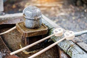 turista lavando as mãos no pavilhão do santuário fushimi inari, localizado em fushimi-ku. Marco e popular para atrações turísticas em kyoto. texto em japonês significa boa sorte foto