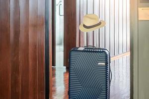 bagagem azul com chapéu no quarto de hotel moderno após a abertura da porta. hora de viajar, serviço, viagem, viagem, férias de verão e conceitos de férias foto