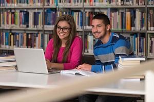casal de estudantes com laptop na biblioteca foto