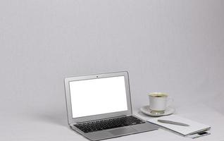 laptop branco com xícara de caneta prata cappuccino na mesa
