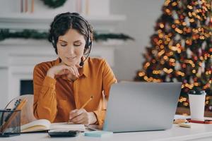 operador de call center feminino europeu em fone de ouvido com microfone trabalhando durante as férias de inverno foto