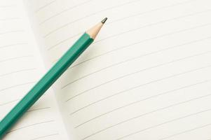 lápis verde em um caderno aberto. layout de conceito de educação mínima com um lápis.