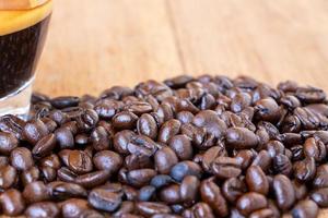 Feche a pilha de grãos de café orgânico torrado marrom escuro em uma mesa de madeira. foco seletivo no meio da pilha de grãos de café foto