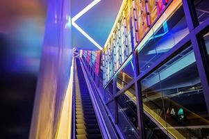 escada rolante com luz led ao lado no tema de luz colorida de néon abstrato de tecnologia. foto