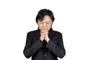 homem de negócios asiáticos isolado em terno preto mão juntos e reza por algo no fundo branco. caminho de recorte. foto