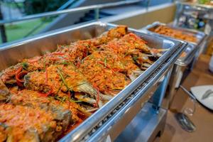 um peixe de comida tailandesa frito em um molho picante em placa de triângulo de alumínio no buffet de linha em frente à sala de seminários. foto