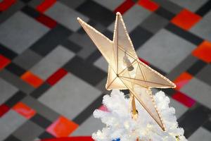 a grande decoração de estrela dourada no topo da árvore de natal. foto