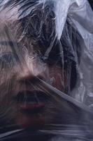 mulher com o rosto coberto por uma folha de plástico foto