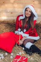 linda garota fantasiada de papai noel senta-se na palha foto