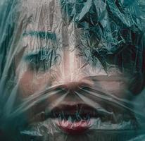 mulher com o rosto coberto por uma folha de plástico como resultado do vírus corona foto