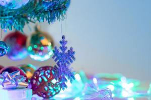 fechar o floco de neve e bolas de natal penduradas no galho do pinheiro foto