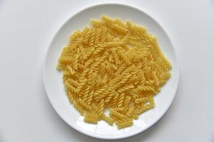 macarrão cru torcido amarelo em um prato branco foto