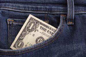 uma nota de dólar em um bolso de jeans azul foto