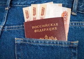 notas de rublo russo e passaporte no bolso de trás da calça jeans foto