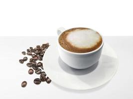 xícara de café e feijão na mesa branca foto