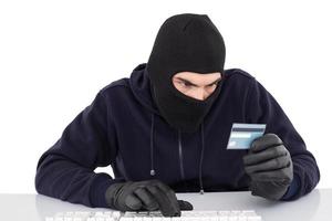 assaltante focado usando computador e cartão de débito