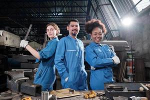 trabalhadores multirraciais da indústria em uniformes de segurança colaboram com a unidade, agem com ferramentas e expressam um trabalho feliz junto com sorriso e alegre na fábrica mecânica, ocupação profissional de engenheiro. foto